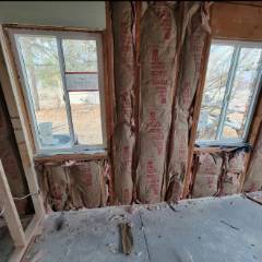 Interior renovation showing exposed wooden studs and framing between two windows