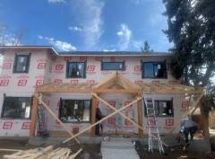 Home under construction with pink insulation, wooden framing, and metal scaffolding