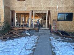Storefront entrance with glass doors and windows, snow on ground, brick building facade