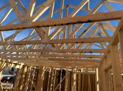 Wooden roof trusses and framing against blue sky during construction